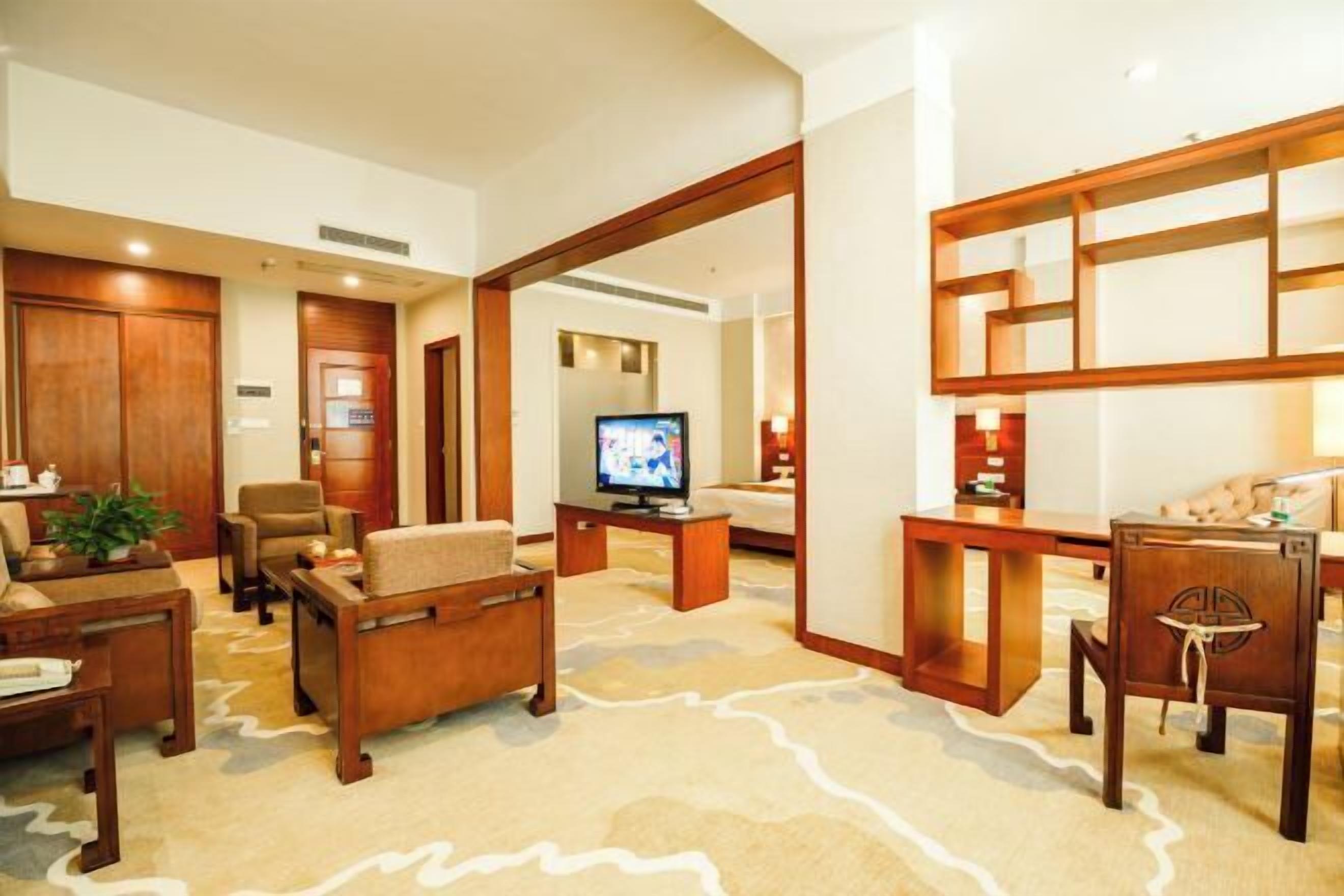 A hotel lobby with a wooden reception desk, a television, and seating arrangements.