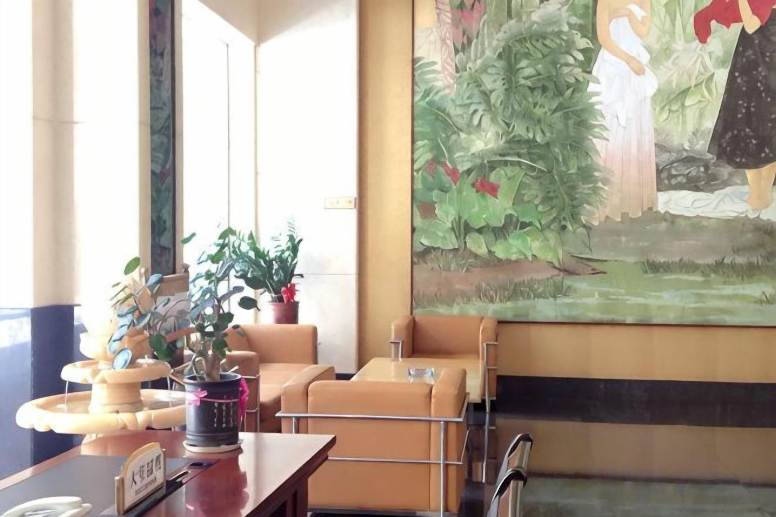 A hotel lobby with a reception desk, seating area, and a large mural.