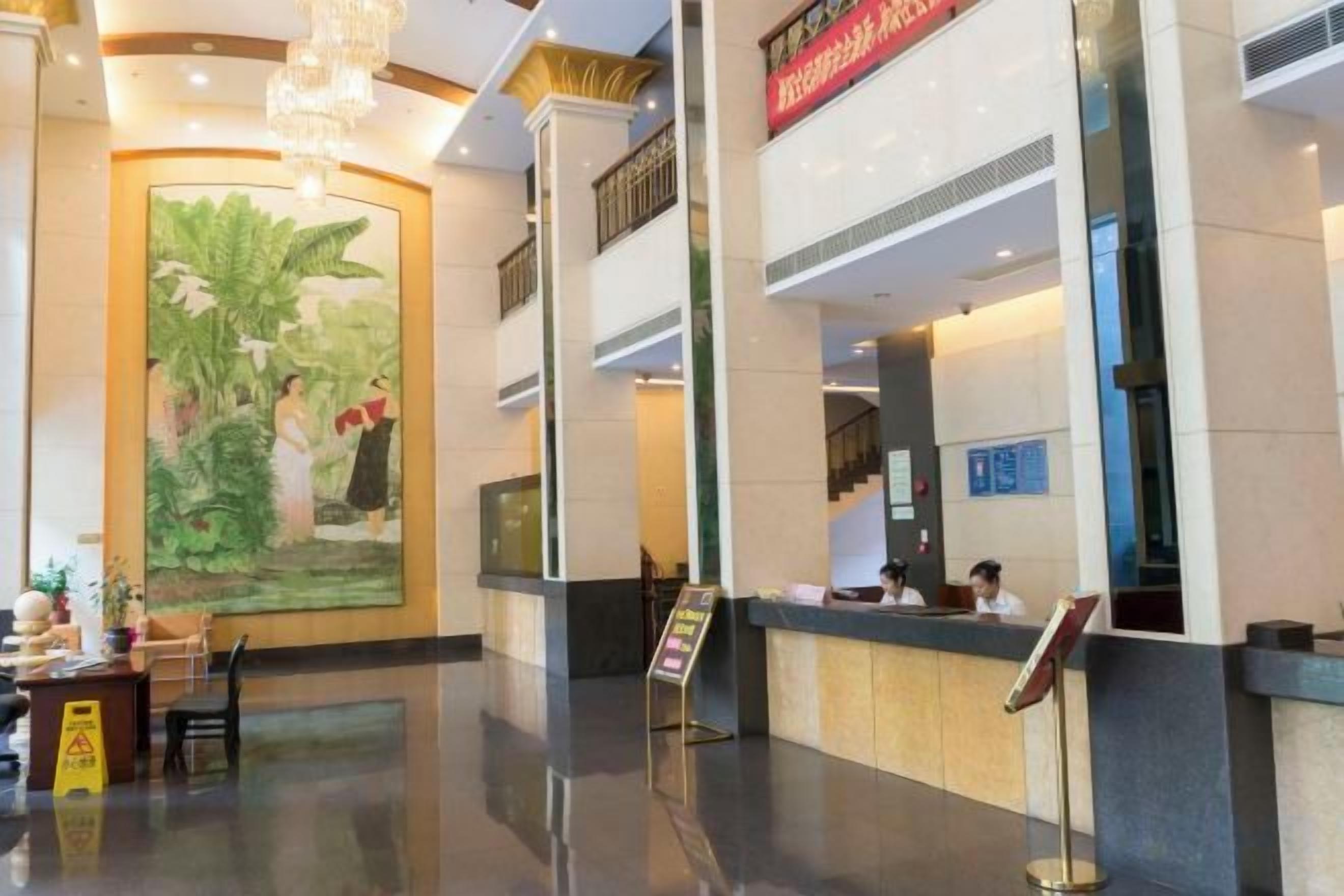 Un vestíbulo de hotel con una recepción, un mural grande y una escalera.
