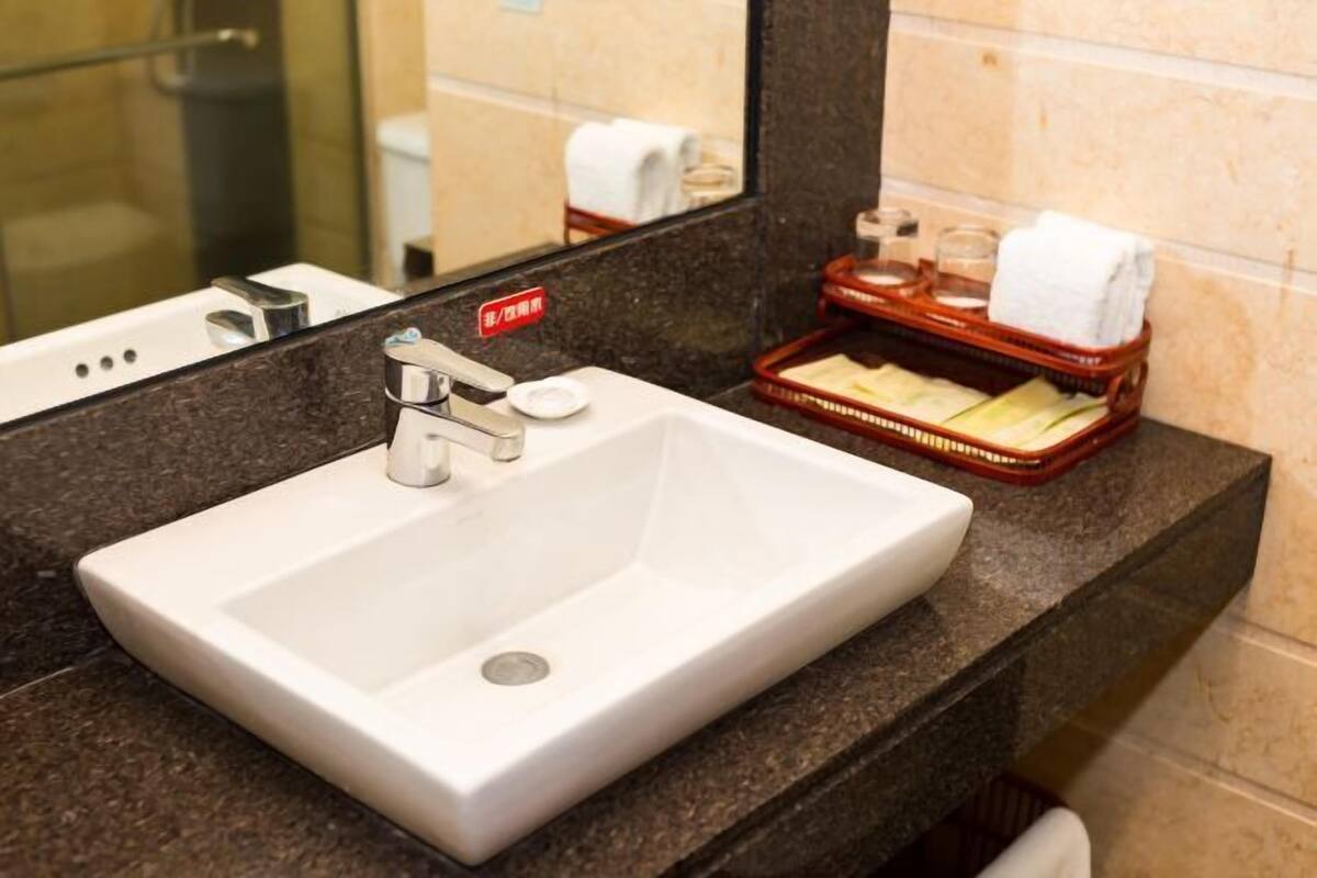 A hotel bathroom with a white sink, a mirror, and a soap dish.