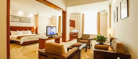 A hotel room with a bed, a television, a desk, a chair, and a sofa.