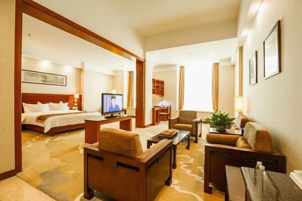 Una habitación de hotel con cama, televisor, escritorio, silla y sofá.