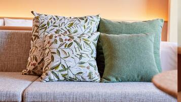 Ein Sofa mit zwei Kissen, eines mit Blattmuster und das andere schlicht grün.