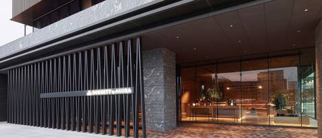 A modern building with a glass entrance, a metal railing, and a sign that reads "DORSEIT AGORA".