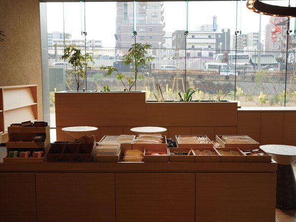 A modern interior with a wooden counter displaying various items, a large window with a city view, and indoor plants. - Dorsett by Agora Osaka Sakai (Sakai)