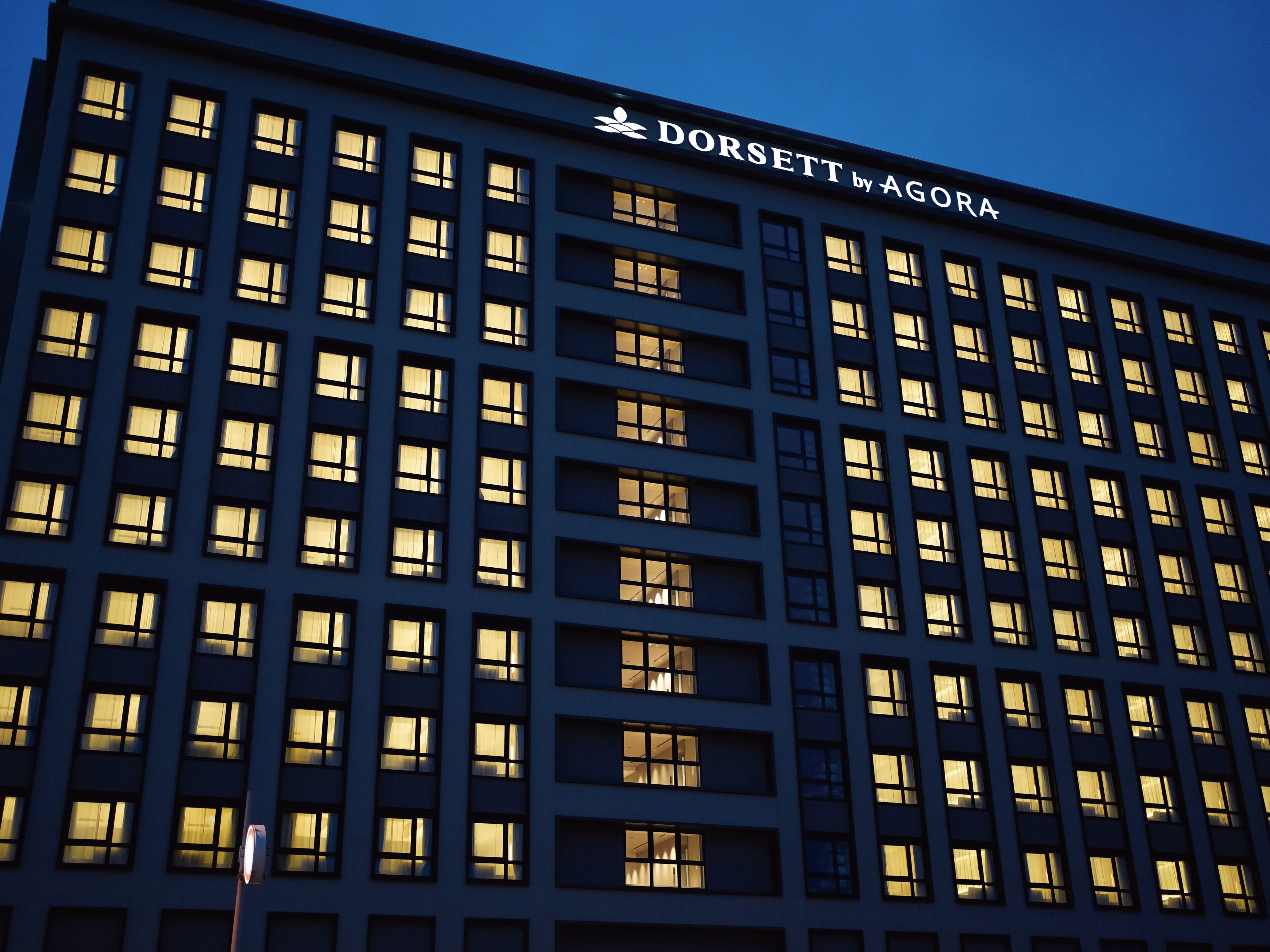 A multi-story building with a grid of windows and a sign reading "DORSETT by AGORA".