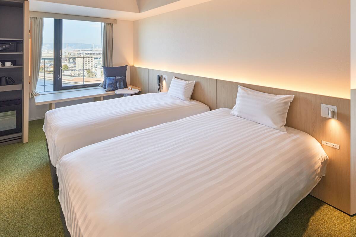 Habitación de hotel con dos camas, un escritorio, vistas a la ciudad y un minibar.