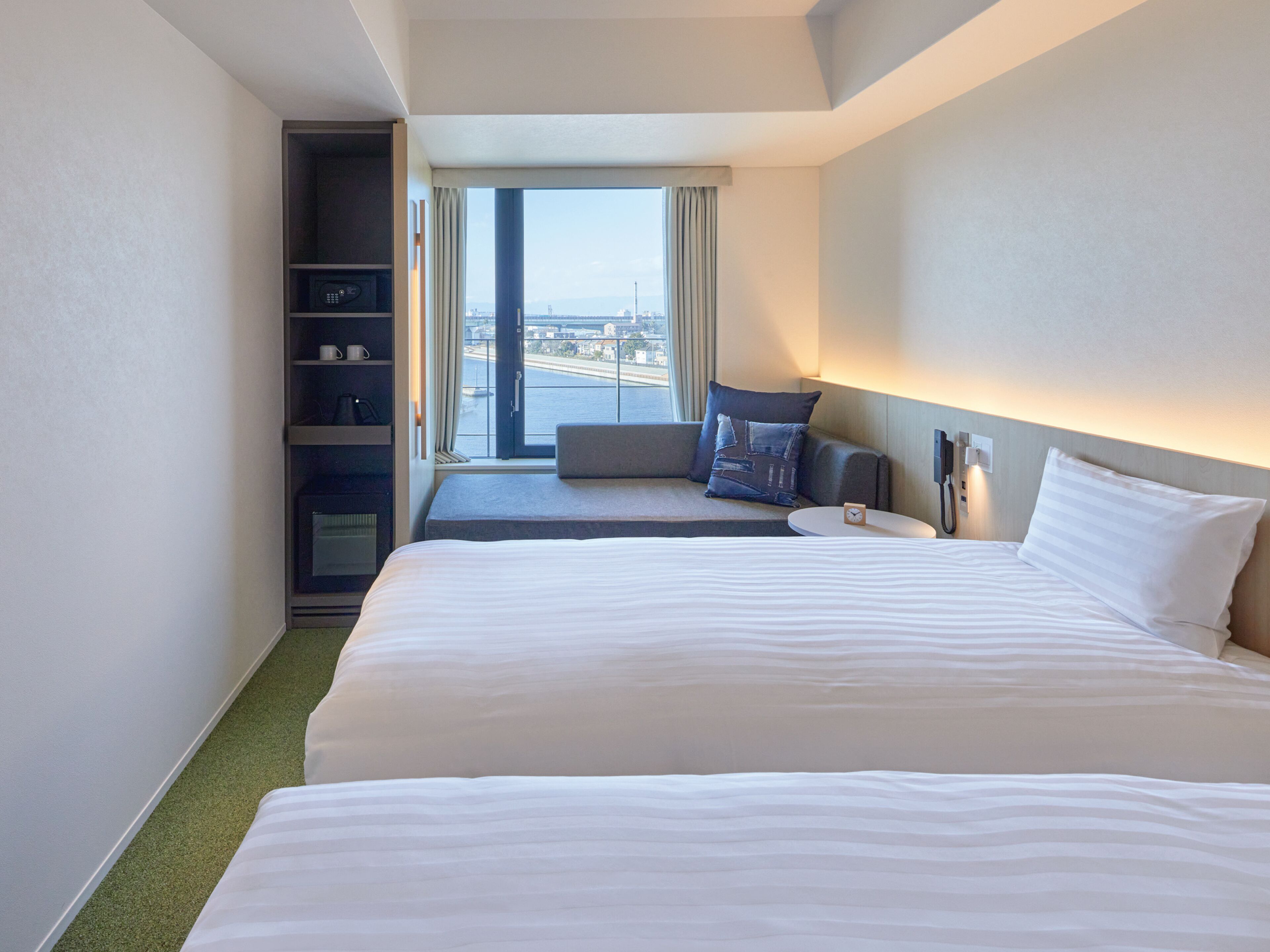 A hotel room with a large bed, a seating area with a view, and a minibar.