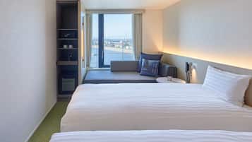 A hotel room with a large bed, a seating area with a view, and a minibar.