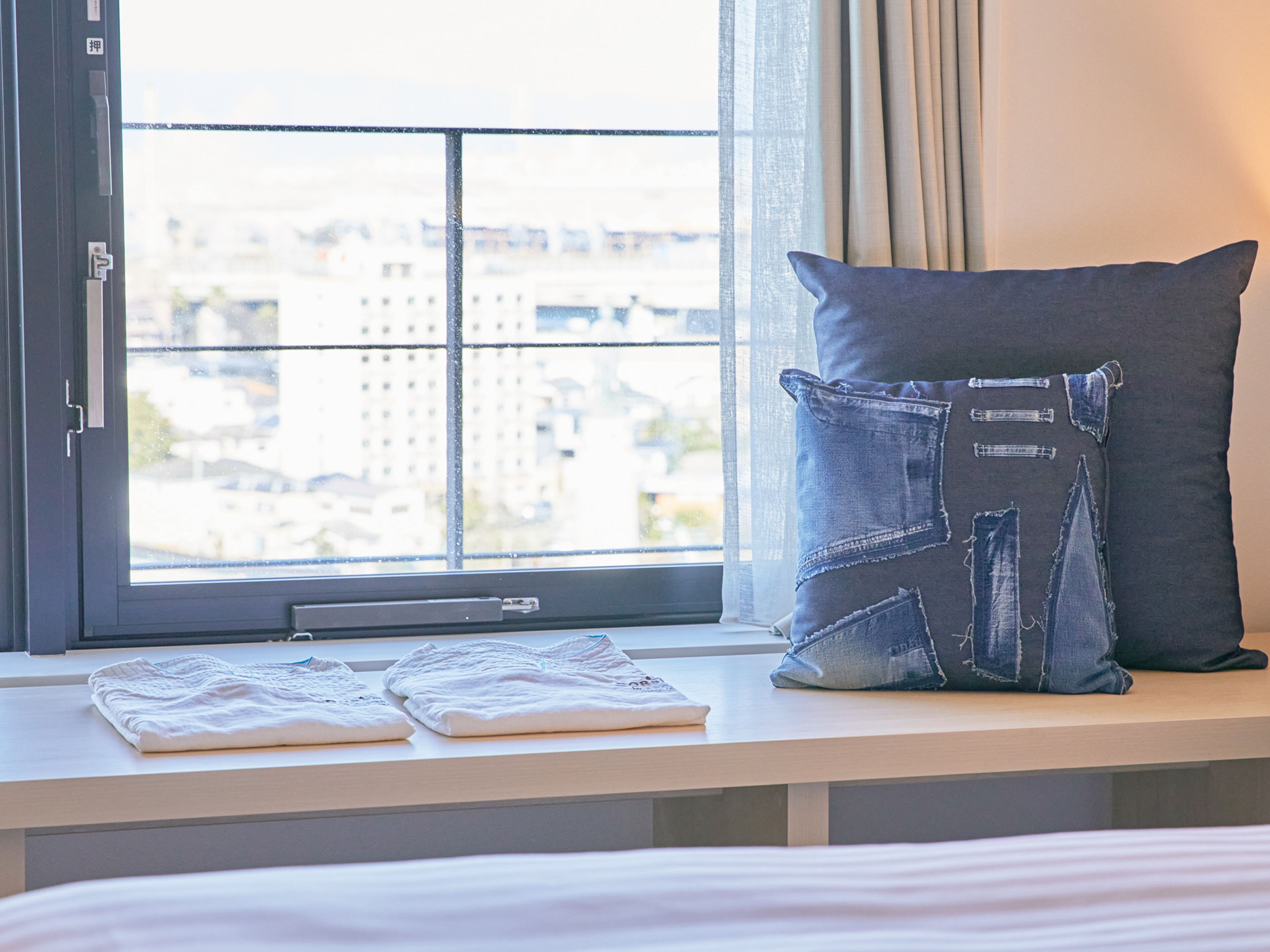 Habitación de hotel con cama, ventana que ofrece vistas a edificios y almohada con diseño vaquero.