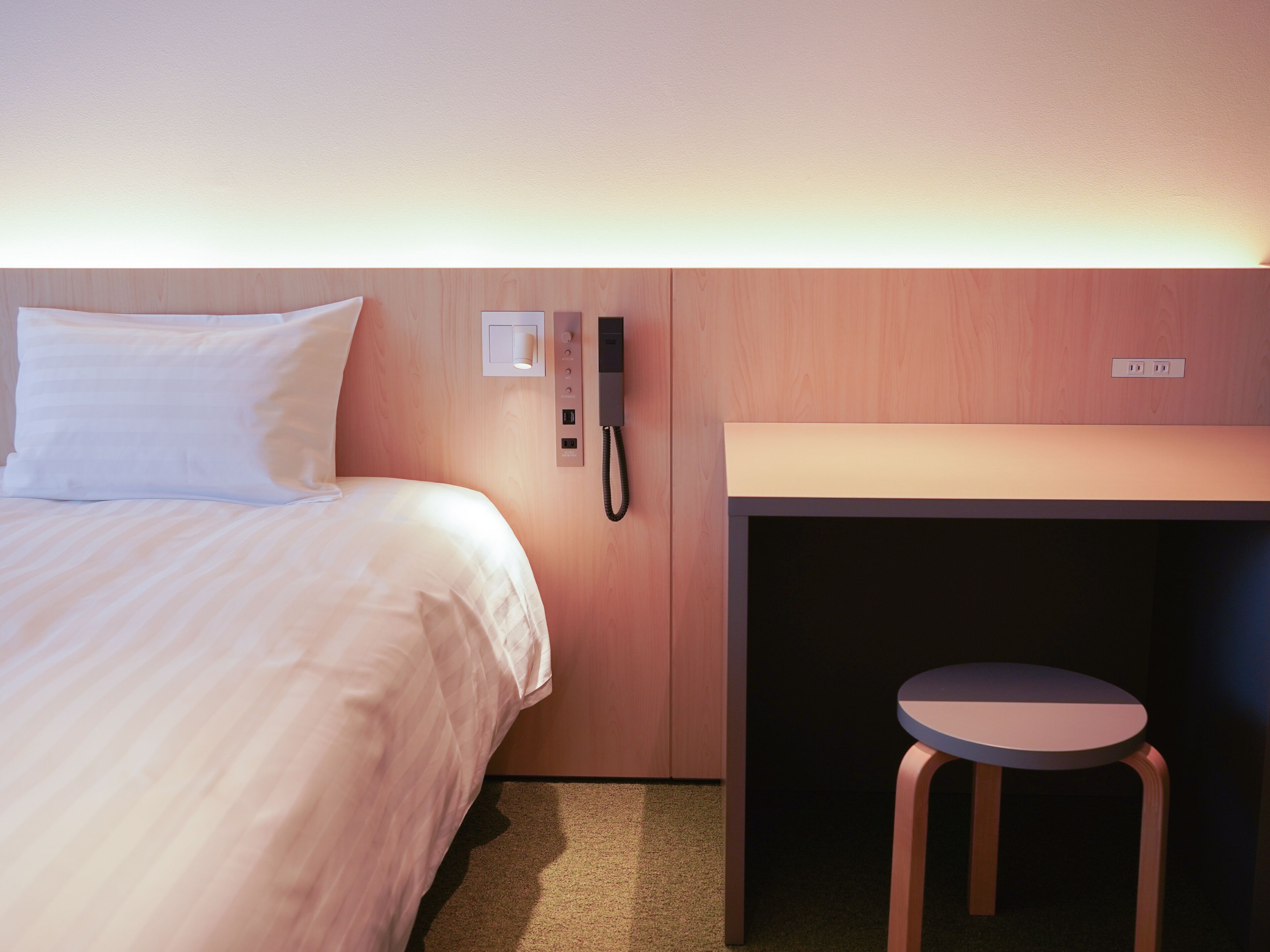 Habitación de hotel con cama, escritorio, silla y teléfono.
