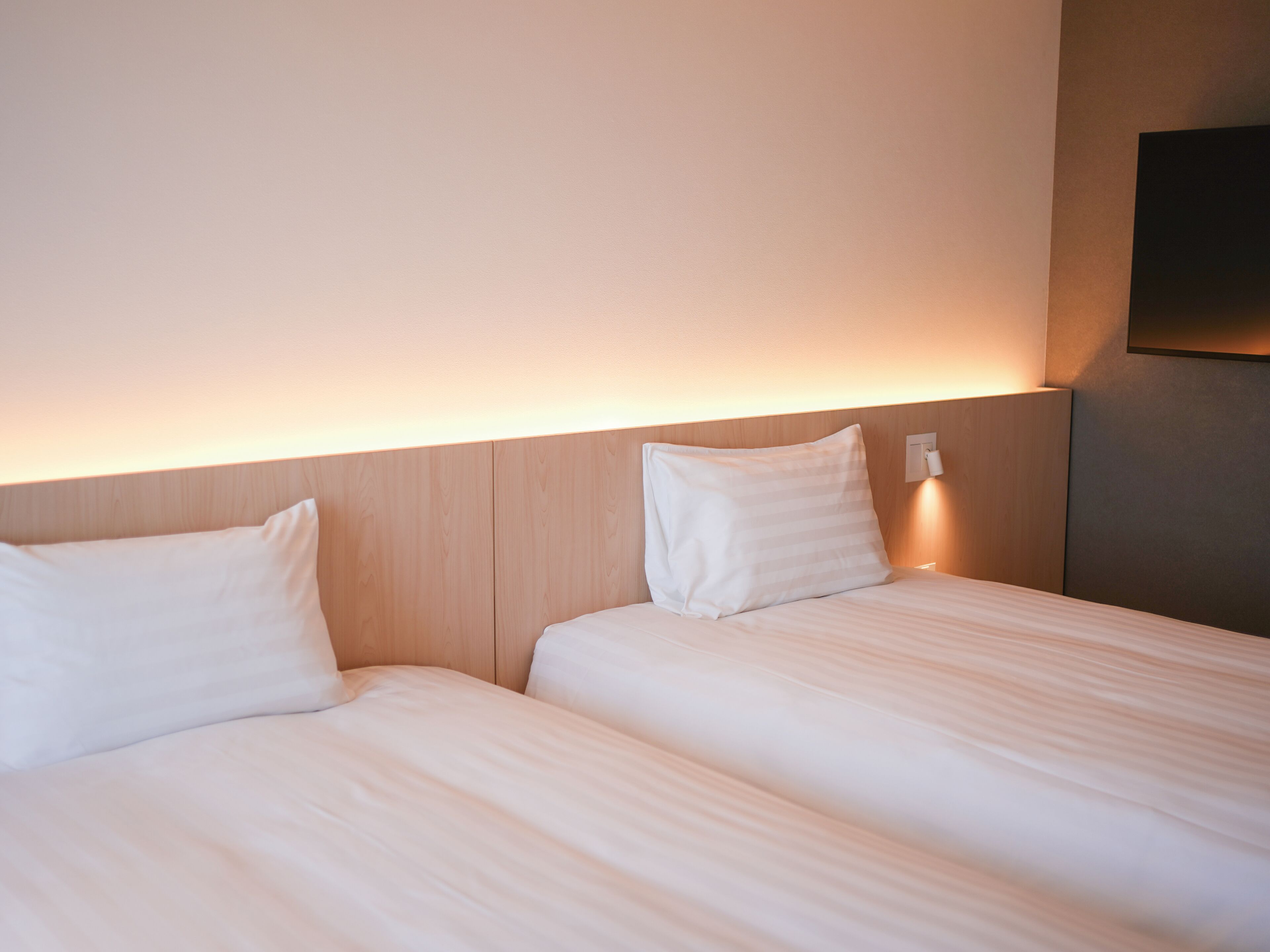 Two single beds with wooden headboards and white bedding in a hotel room.