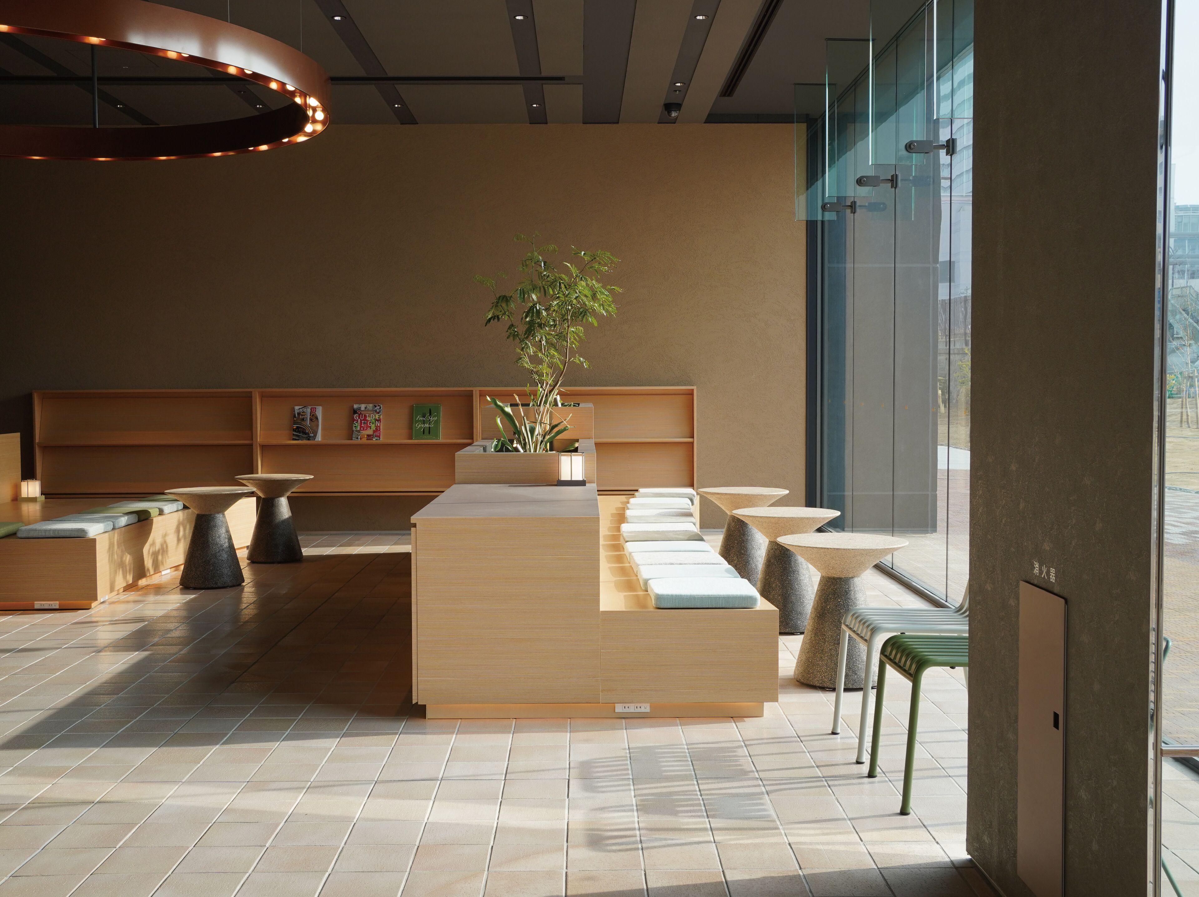 A modern interior with a long reception desk, seating area, and a large window providing a view of the outside.