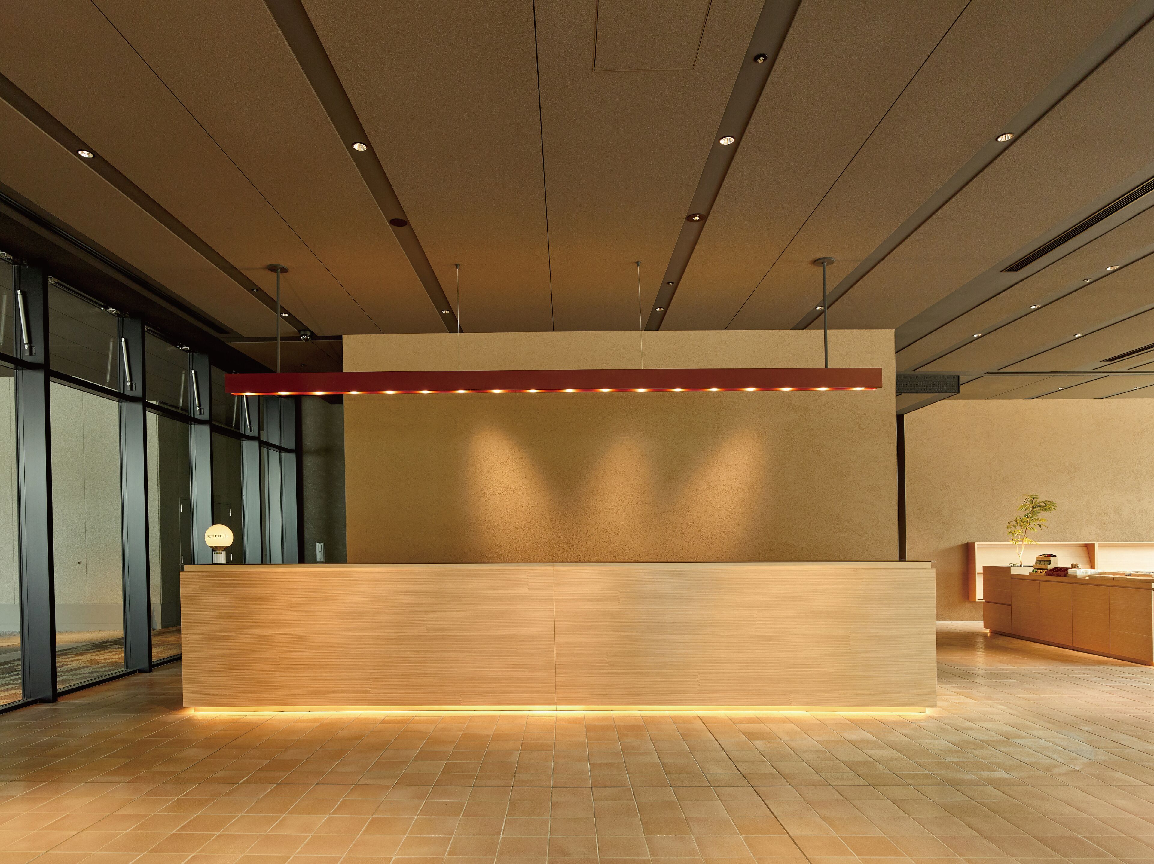 A reception desk with a wooden finish, recessed lighting, and a red accent strip.