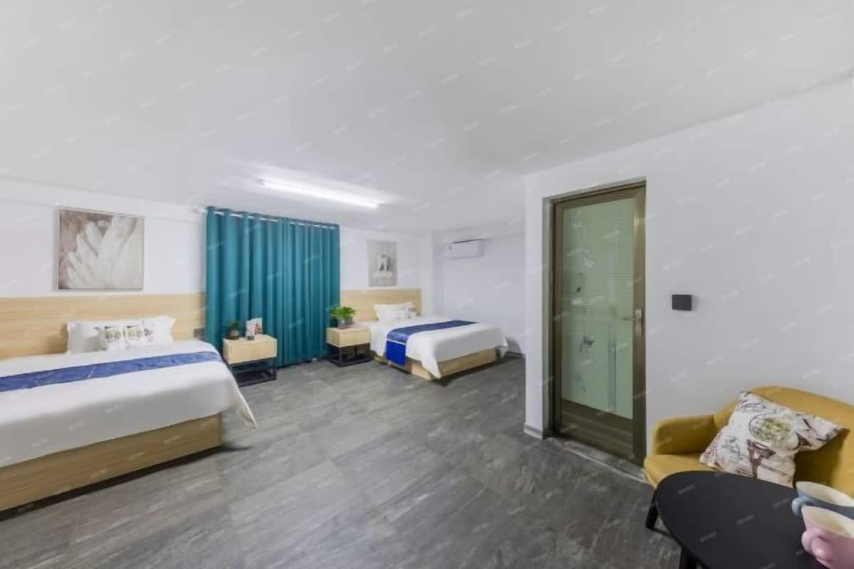 A hotel room with two beds, a sofa, a table, a window with curtains, and a door.
