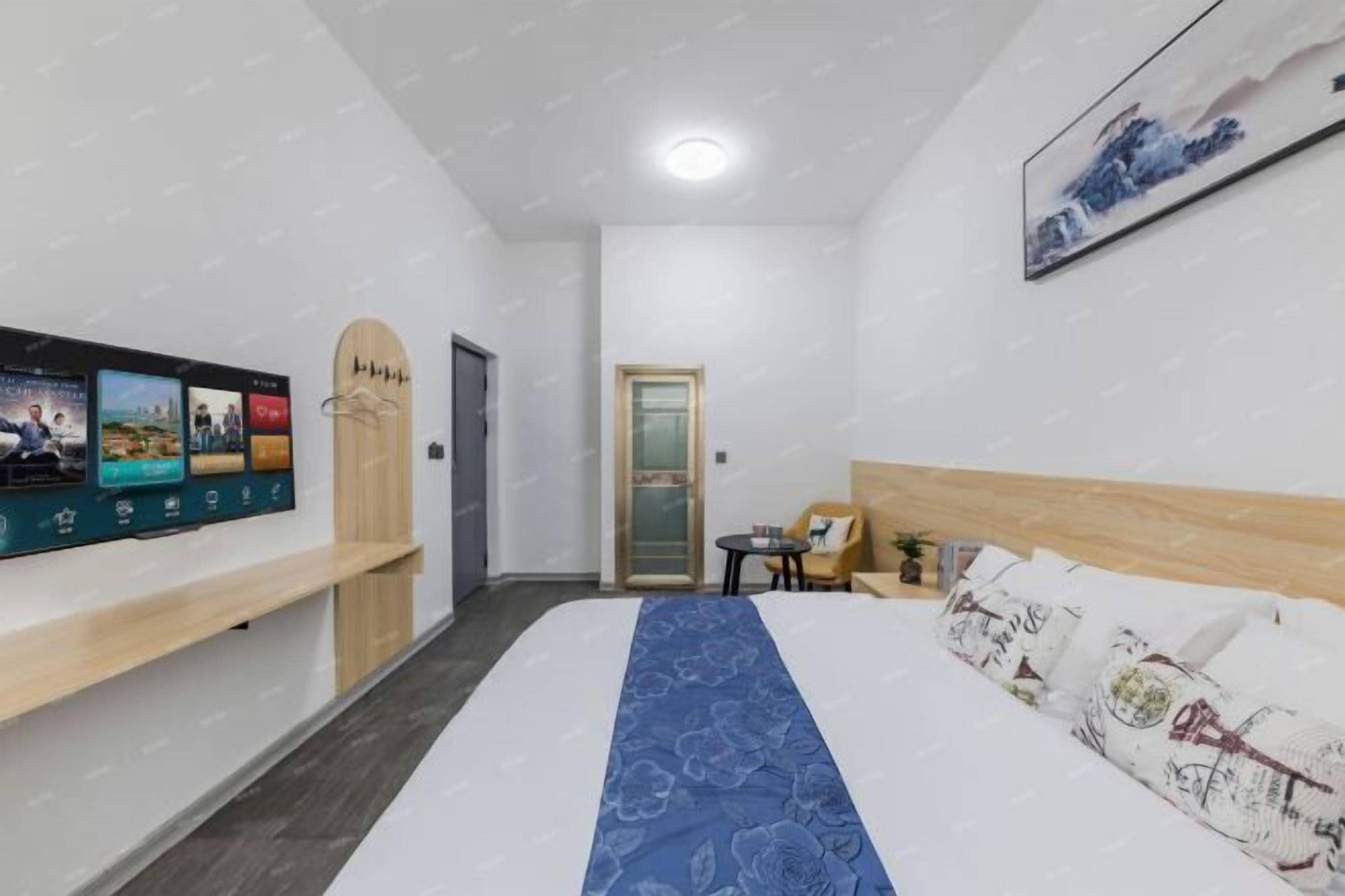 A hotel room with a bed, a TV mounted on the wall, a small table, and a chair.