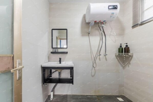 Ein kleines Badezimmer mit einem weißen Waschbecken, einem Spiegel, einer Handbrause und einem Wandheizkörper.