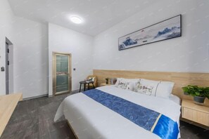 Ein Hotelzimmer mit einem Bett, einem Nachttisch, einem Sessel, einem Schreibtisch und einer Tür.