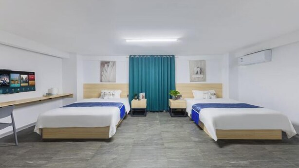 A hotel room with two beds, a desk, a TV, and a window with curtains. - Youranju Inn (Xiamen)