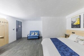 Ein modernes Hotelzimmer mit einem Bett, einer blauen Couch, einem Holzschrank und einer Tür.