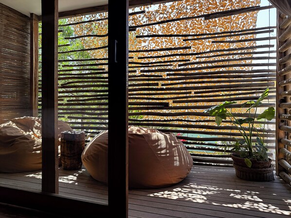 A wooden deck with a bamboo screen, a bean bag, and a potted plant. - Ecolodge Mancora (Máncora)