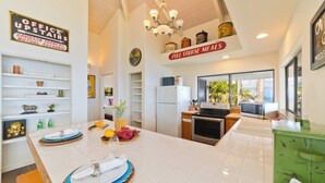A modern kitchen with a large island, white cabinetry, and a view of the outdoors. - Tranquil Ocean View Cottage: Your Idyllic Escape at Waipio Valley, Big Island HI (Honokaa)