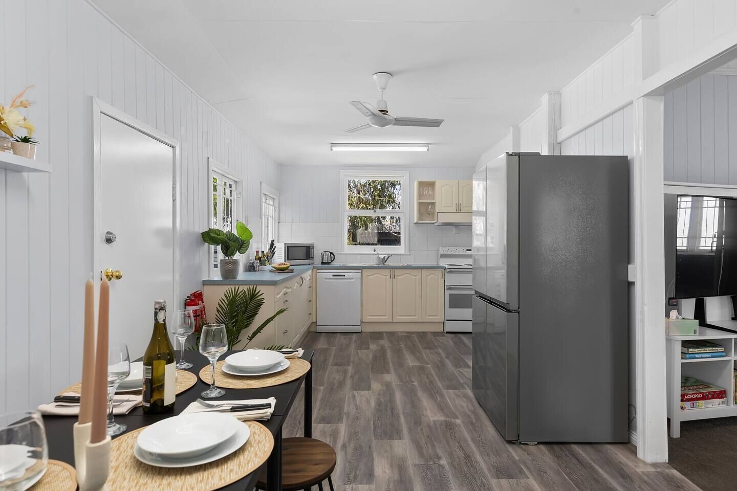 Una cocina moderna con armarios blancos, un refrigerador gris y un comedor listo para una comida.