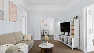 Un salon avec un canapé, une table basse, un téléviseur posé sur un meuble et une bibliothèque.