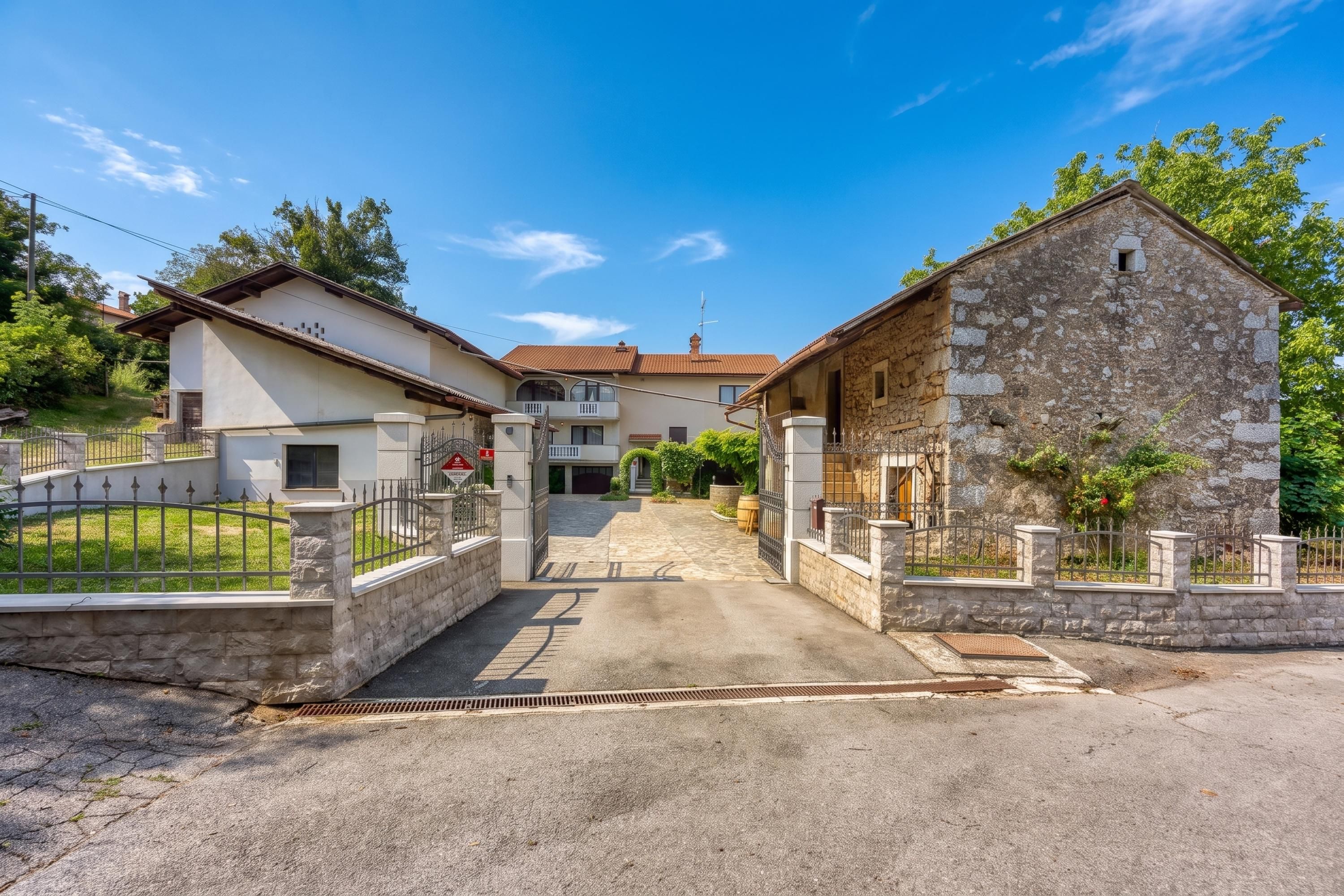 A residential street with houses, a gated entrance, and a clear sky.
