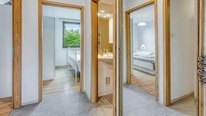 Un couloir avec des portes en bois donnant accès à une salle de bain et à une chambre.