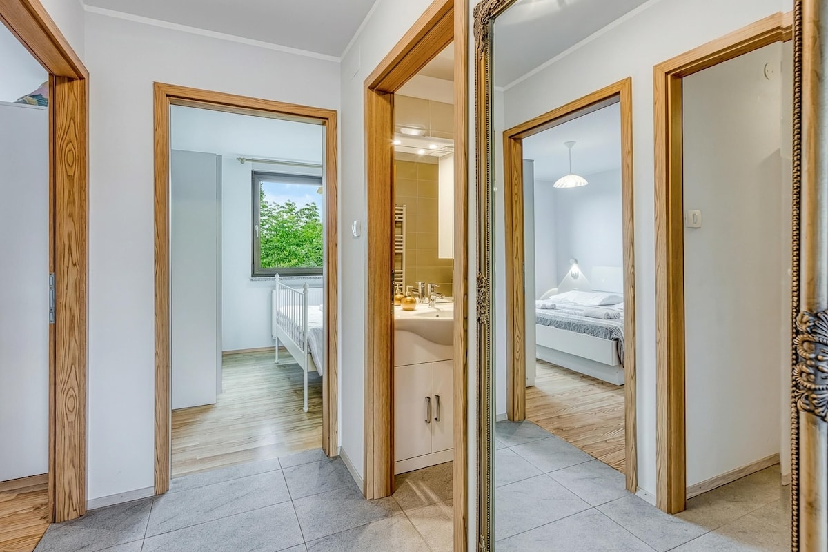 Corredor com portas de madeira que dão para um banheiro e um quarto.