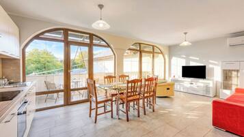 Cocina moderna con una isla, comedor con sillas de madera, un sofá rojo y un televisor.