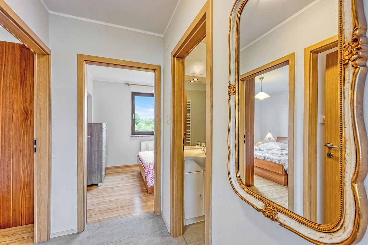 Corredor que leva a um quarto, com um espelho grande e uma porta de madeira.