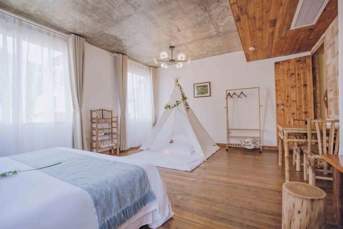 A room with a bed, a wooden chair, a tent, and a ladder.