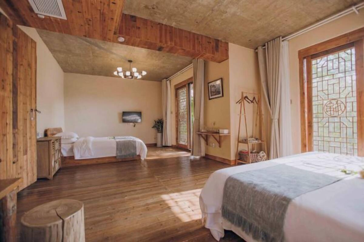 A room with wooden floors, a bed, a desk, and a TV.