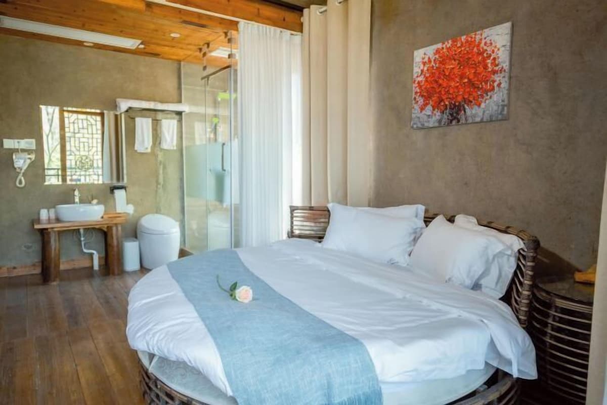 A bedroom with a bed, a bedside table, a sink, and a shower.