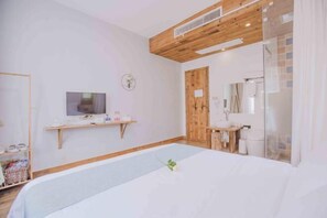 A bedroom with a bed, a TV, a wooden shelf, a wooden door, and a bathroom with a mirror and sink. - Jushe village Meisu Inn (Deqing)