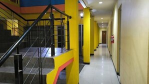 A hotel corridor with a staircase, yellow pillars, and a fire extinguisher. - Hotel Simpang Lima Semarang (South Semarang)