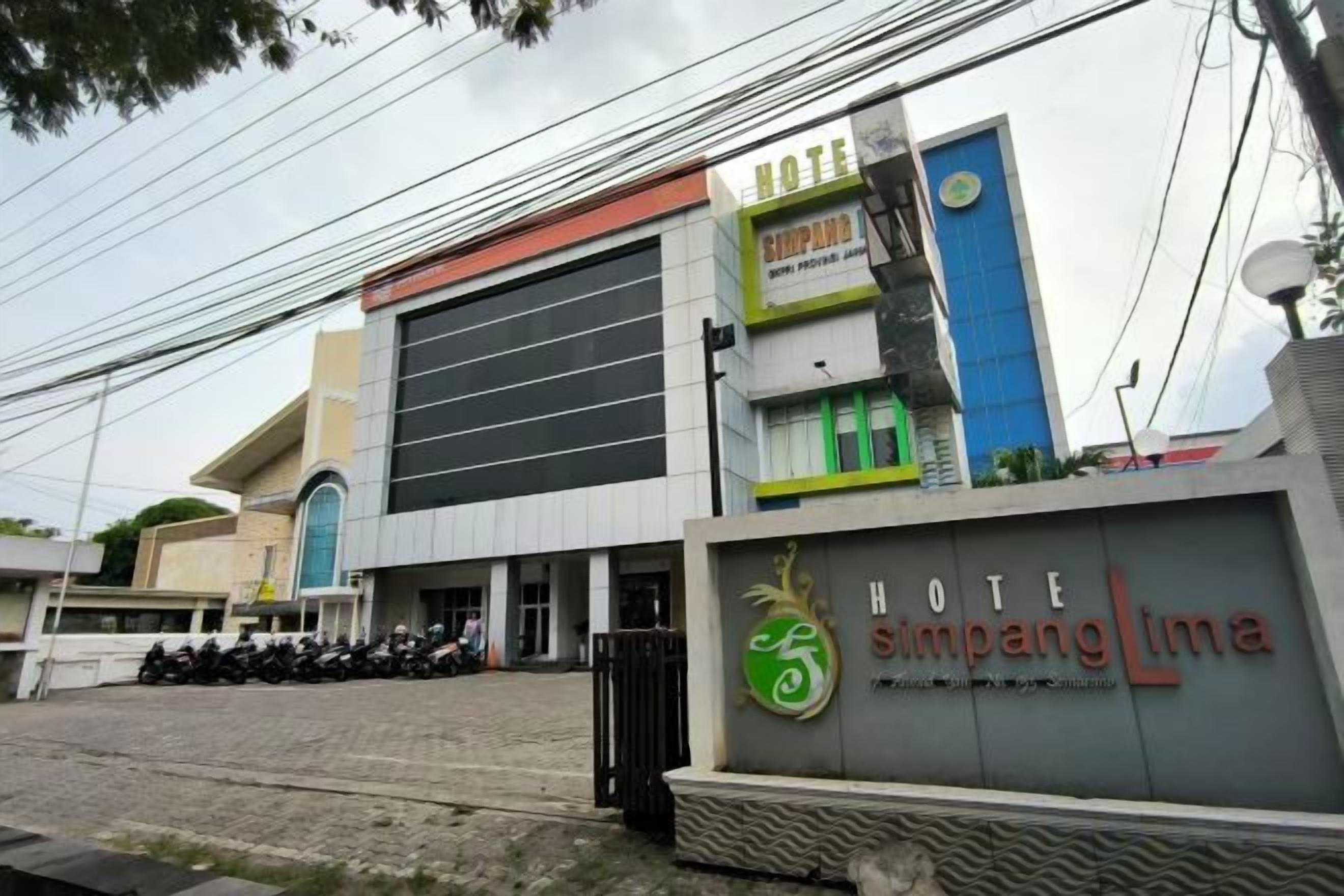 L’entrée d’un hôtel, avec une enseigne indiquant « HÔTEL Simpang Lima ».
