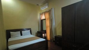 A bedroom with a bed, an air conditioning unit, a wardrobe, and a small table. - Hotel Simpang Lima Semarang (South Semarang)