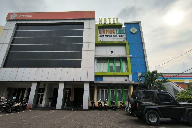 A hotel with a large building, a parking area with motorcycles, and a visible sign for a bank.