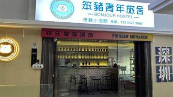 Un hostal con un letrero que indica que se llama 'BONJOUR HOSTEL' e incluye un número de teléfono.