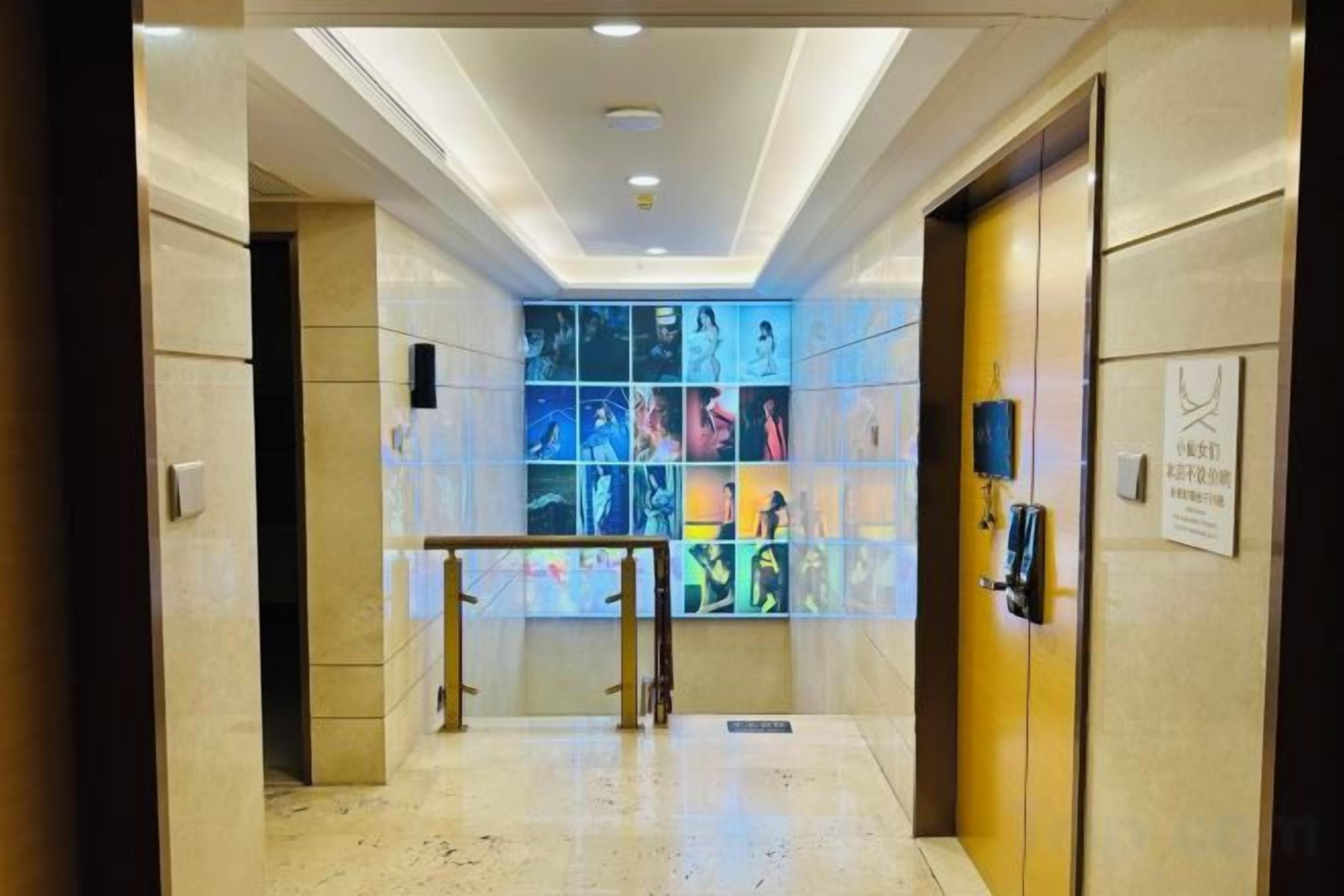 A hotel lobby with a glass wall displaying photos, a reception desk, and a door with a sign.