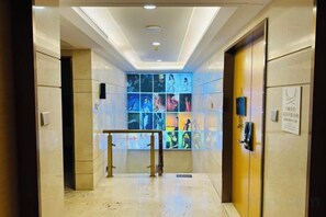 A hotel lobby with a glass wall displaying photos, a reception desk, and a door with a sign. - Bonjour Youth Hostel (Shenzhen)