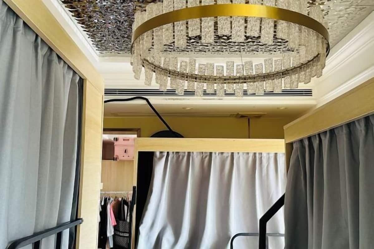 A room with a chandelier, a wardrobe, and a bed with a headboard.