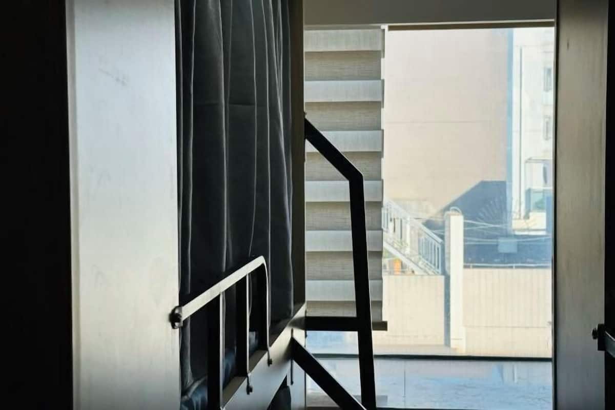 A view through a window with a metal railing, a staircase, and a building in the background.