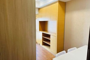 A room with a wooden cabinet, white chairs, and a wooden floor. - Bonjour Youth Hostel (Shenzhen)