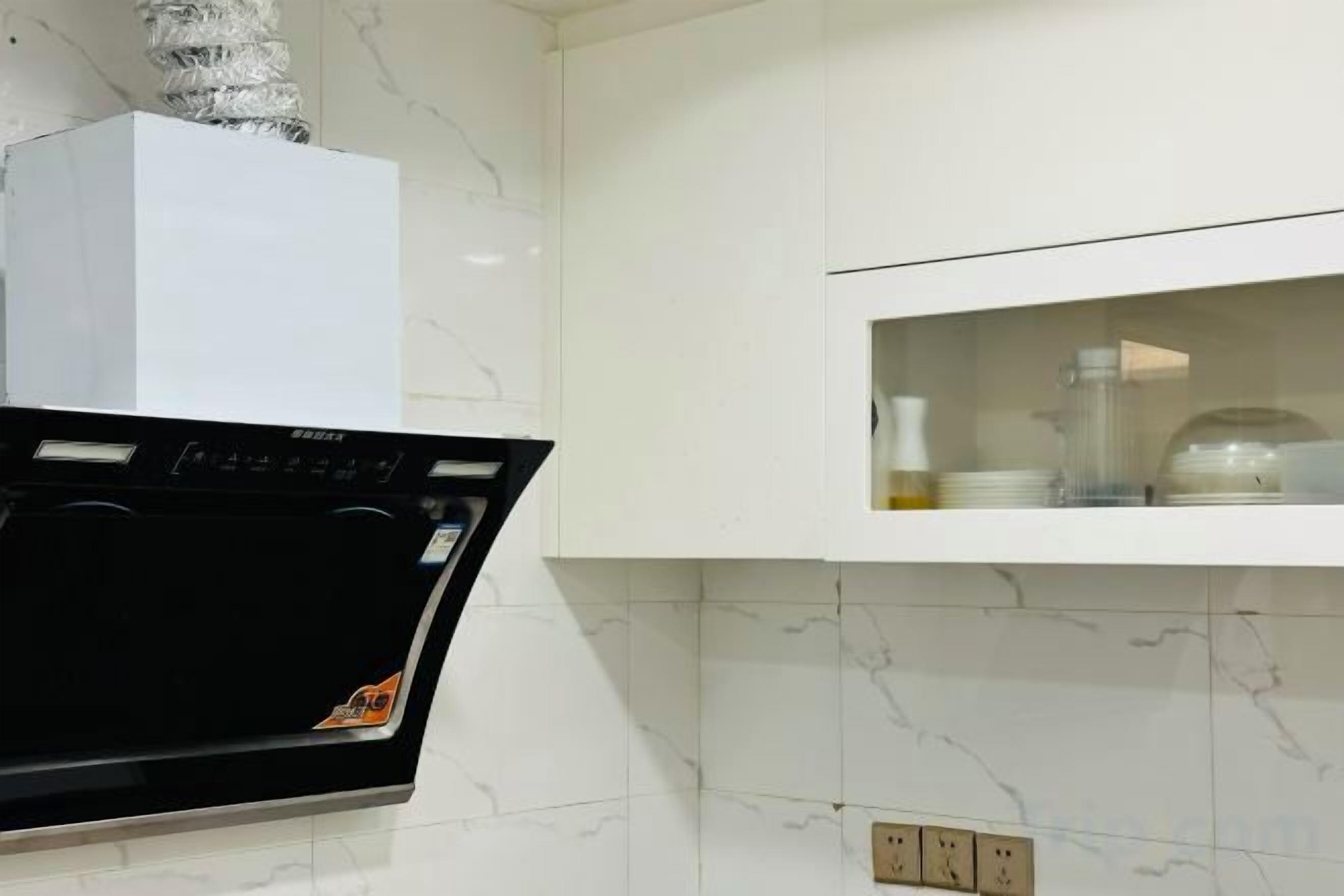 Una cocina con horno negro, armarios blancos y salpicadero de mármol.