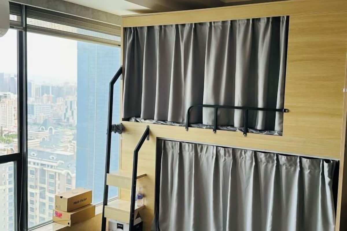 A room with a large window, curtains, and a wooden shelf with boxes.