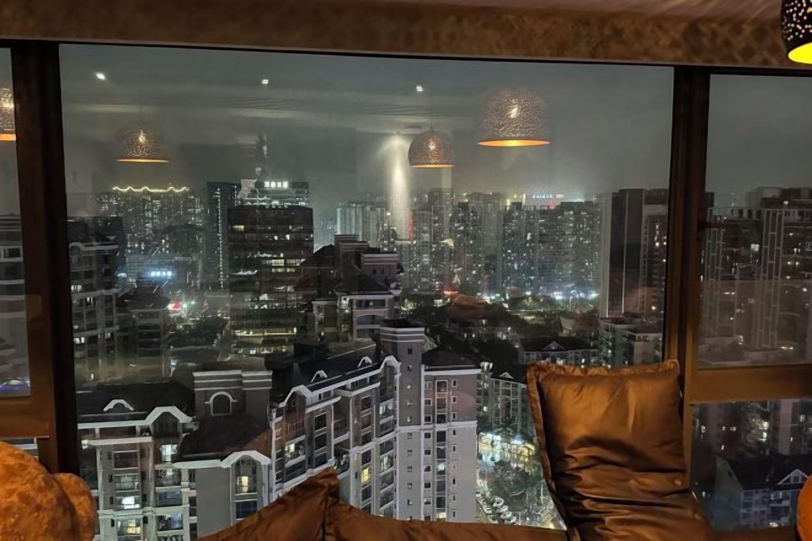 Una habitación con un amplio ventanal que da a una vista nocturna de la ciudad.